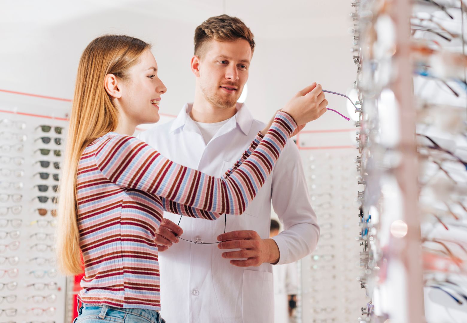 Opticien avec une cliente qui regarde des modèles de lunettes dans une boutique d'opticien